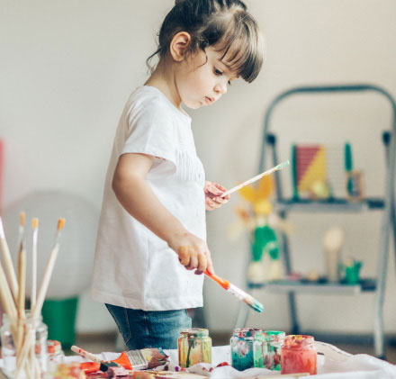 Niña pequeña con pinceles y pinturas